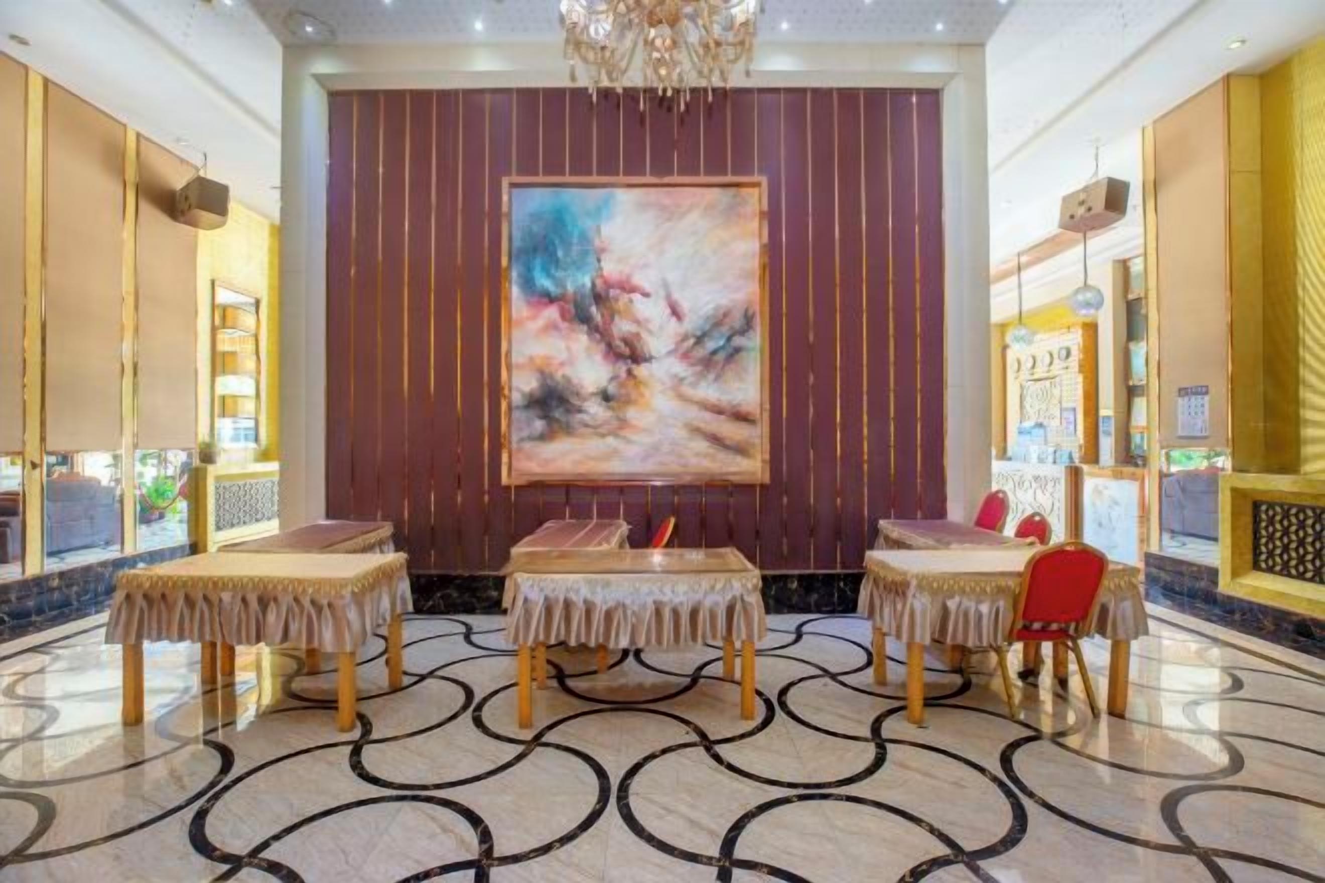 A lobby with a large abstract painting, a reception desk, and a patterned floor.