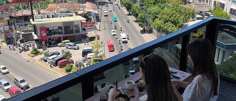 A dining area with a view of a cityscape, including buildings and a street with vehicles.