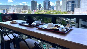 Une table à manger avec de la nourriture, des chaises et une vue sur la ville.
