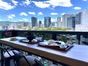 Une table à manger avec de la nourriture, des chaises et une vue sur la ville.