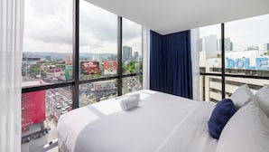 Une chambre d’hôtel moderne avec un grand lit, une vue sur le paysage urbain et une fenêtre avec un rideau.