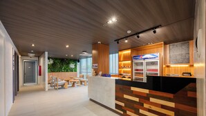Un espace d’accueil moderne comprenant un comptoir d’accueil en bois, un coin salon et un réfrigérateur de la marque FUJIZO.