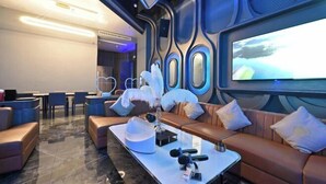 Un área de descanso moderna con sofás de cuero, una mesa de centro de mármol y una pantalla grande que muestra una vista panorámica.