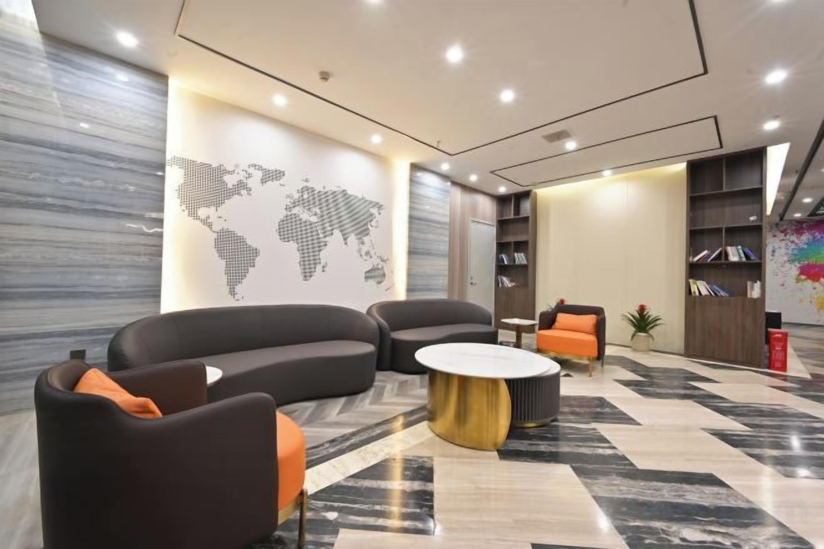 A modern lobby with curved sofas, a round coffee table, and a world map on the wall.