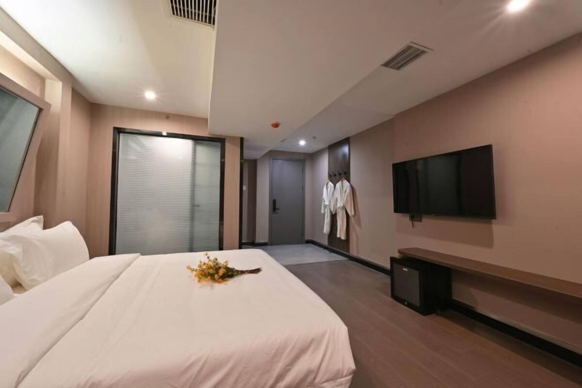 Una habitación de hotel con una cama, televisor, escritorio y armario.