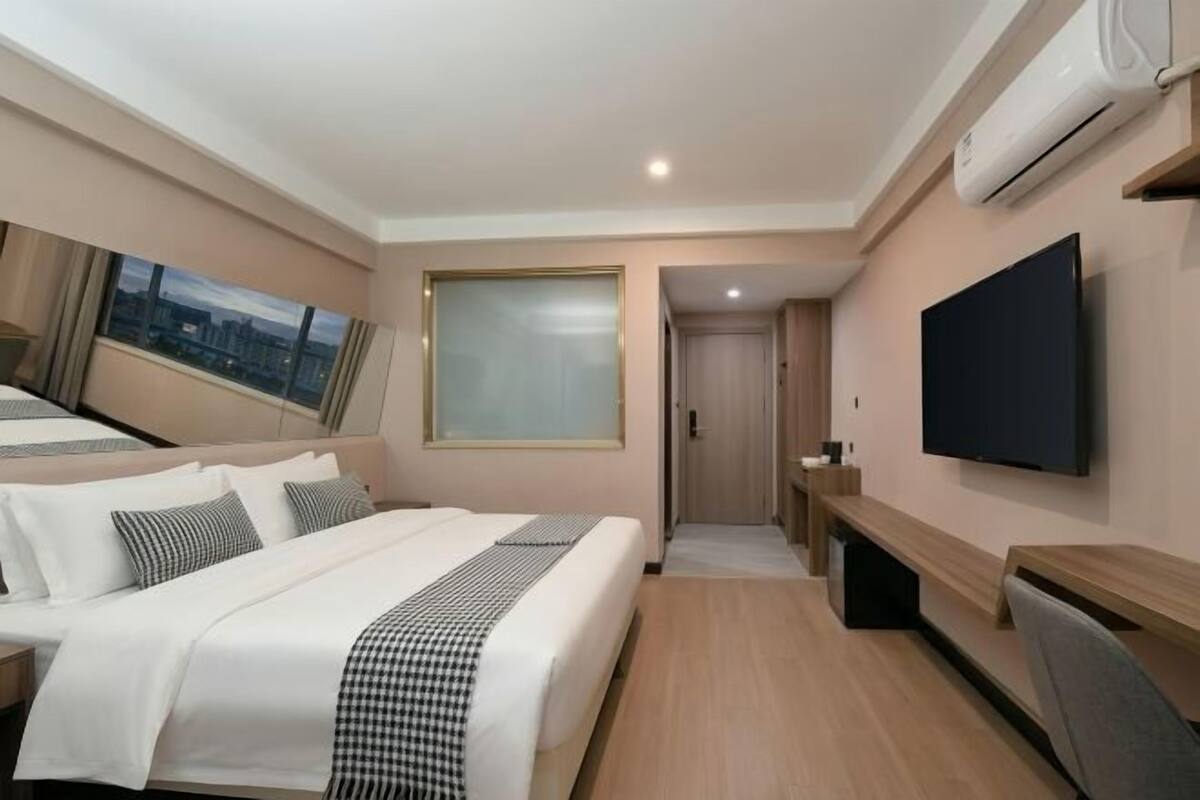 Una habitación de hotel con cama, televisión, escritorio y ventana.