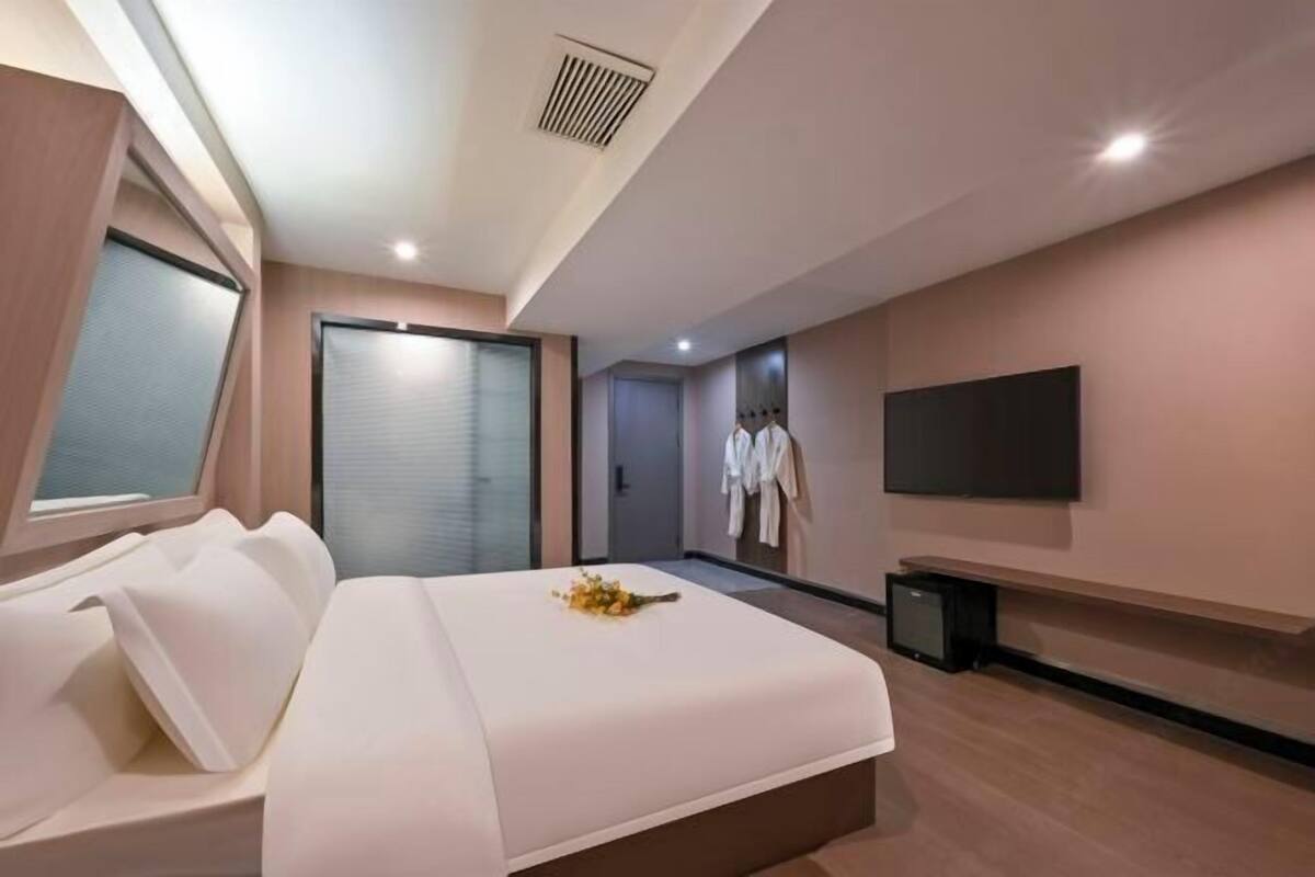 Una habitación de hotel moderna con una cama grande, un televisor y un armario.