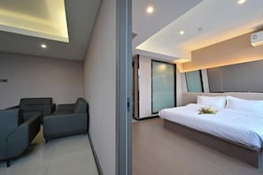 A modern hotel room with a bed, seating area, and a sliding door.