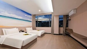 Habitación de hotel con dos camas, un ventanal con vistas a la ciudad, un mural de playa y un televisor de pantalla plana montado en la pared.