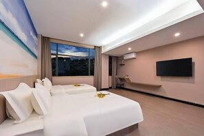 A hotel room with two beds, a TV, a desk, and a city view.