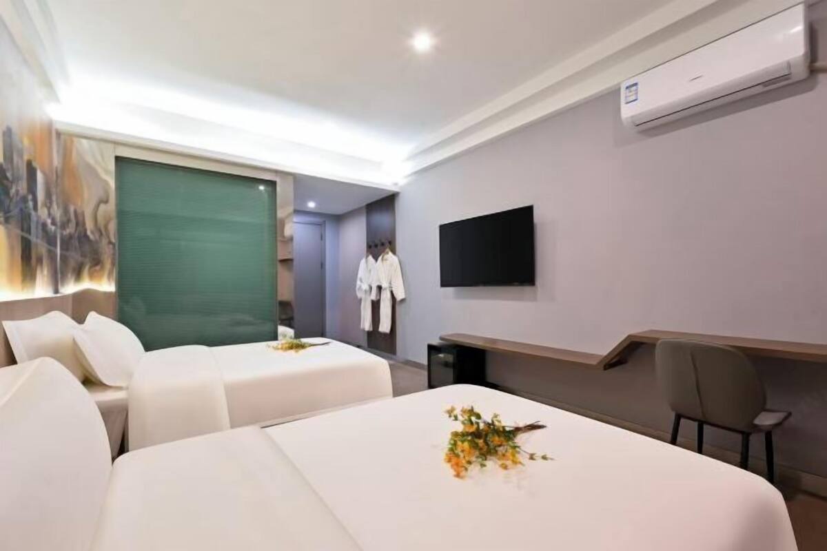 Habitación de hotel con dos camas, un televisor de pantalla plana, aire acondicionado y un cuadro en la pared.
