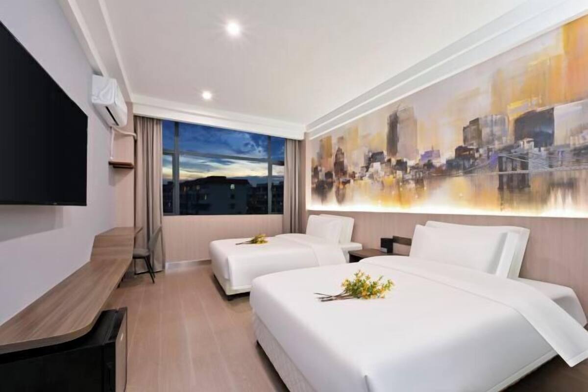 Habitación de hotel con dos camas, un escritorio, un televisor de pantalla plana y vistas a la ciudad.