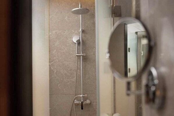 A shower with a handheld showerhead and a wall-mounted control panel.