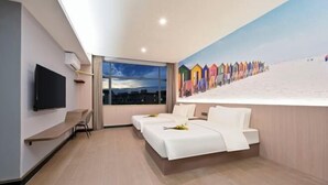 Habitación de hotel con un ventanal grande, un televisor de pantalla plana, un sofá y una cama con ropa blanca.