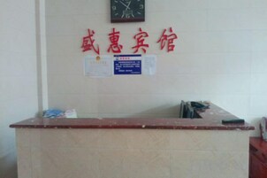 Una recepción con un reloj encima y algunos avisos en la pared.