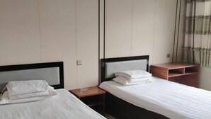 Une chambre d’hôtel avec deux lits, chacun doté d’une table de chevet en bois et d’un oreiller blanc.