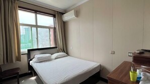 Une chambre d’hôtel avec un lit, un bureau, une chaise et une fenêtre avec des rideaux.