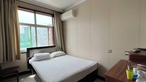 Une chambre d’hôtel avec un lit, un bureau, une chaise et une fenêtre avec des rideaux.