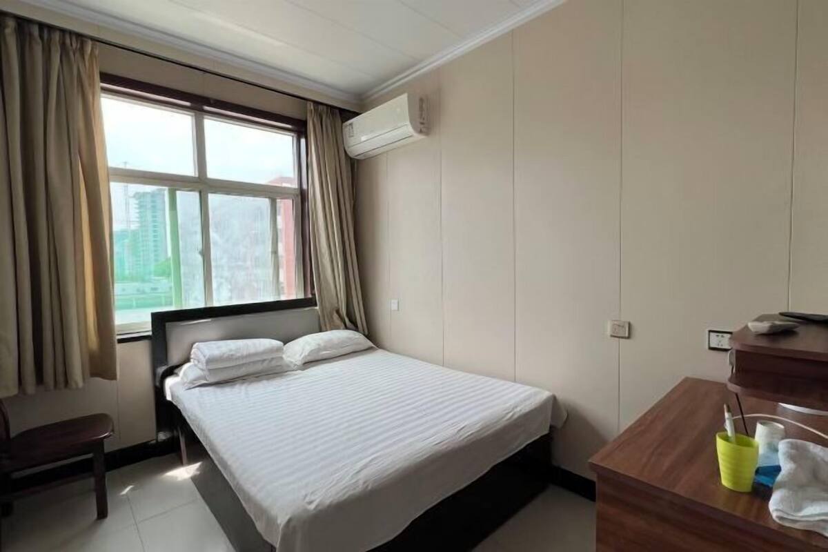 Une chambre d’hôtel avec un lit, un bureau, une chaise et une fenêtre avec des rideaux.