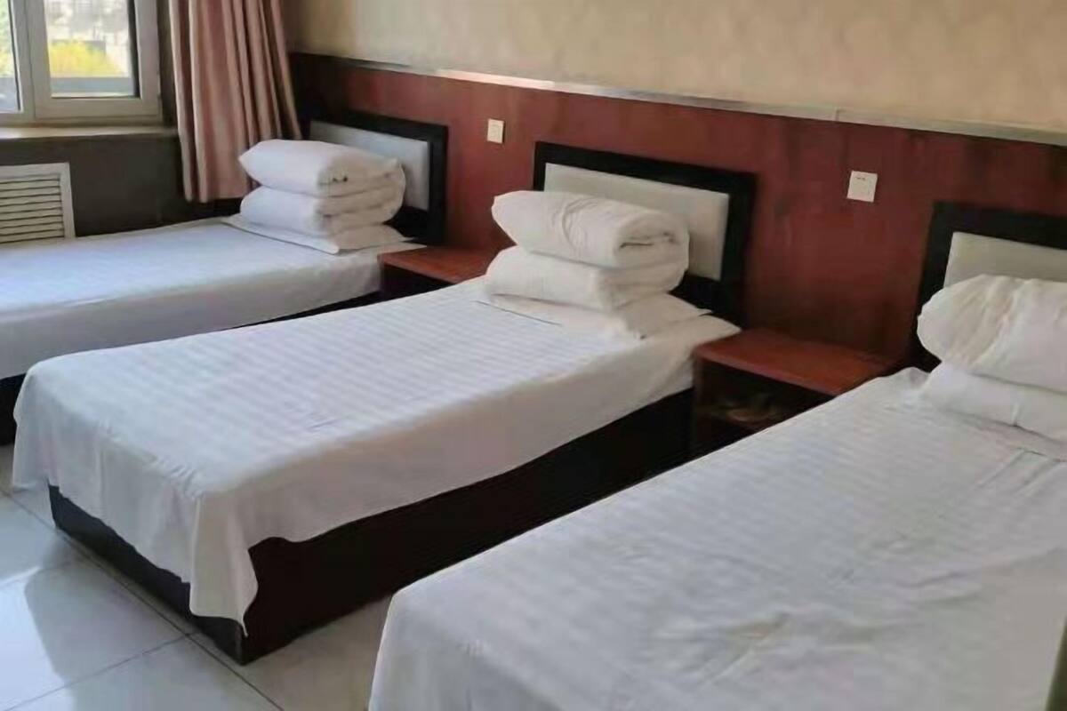 Une chambre d’hôtel avec deux lits simples, chacun étant équipé d’un oreiller et d’une serviette pliée.