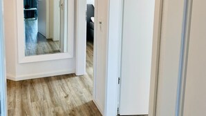 Un couloir doté d’un plancher en bois, de murs blancs et de portes donnant sur d’autres pièces.