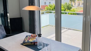 Une pièce moderne comprenant une table à manger, des chaises, une lampe, une bouteille d’eau et une boîte de jeux.