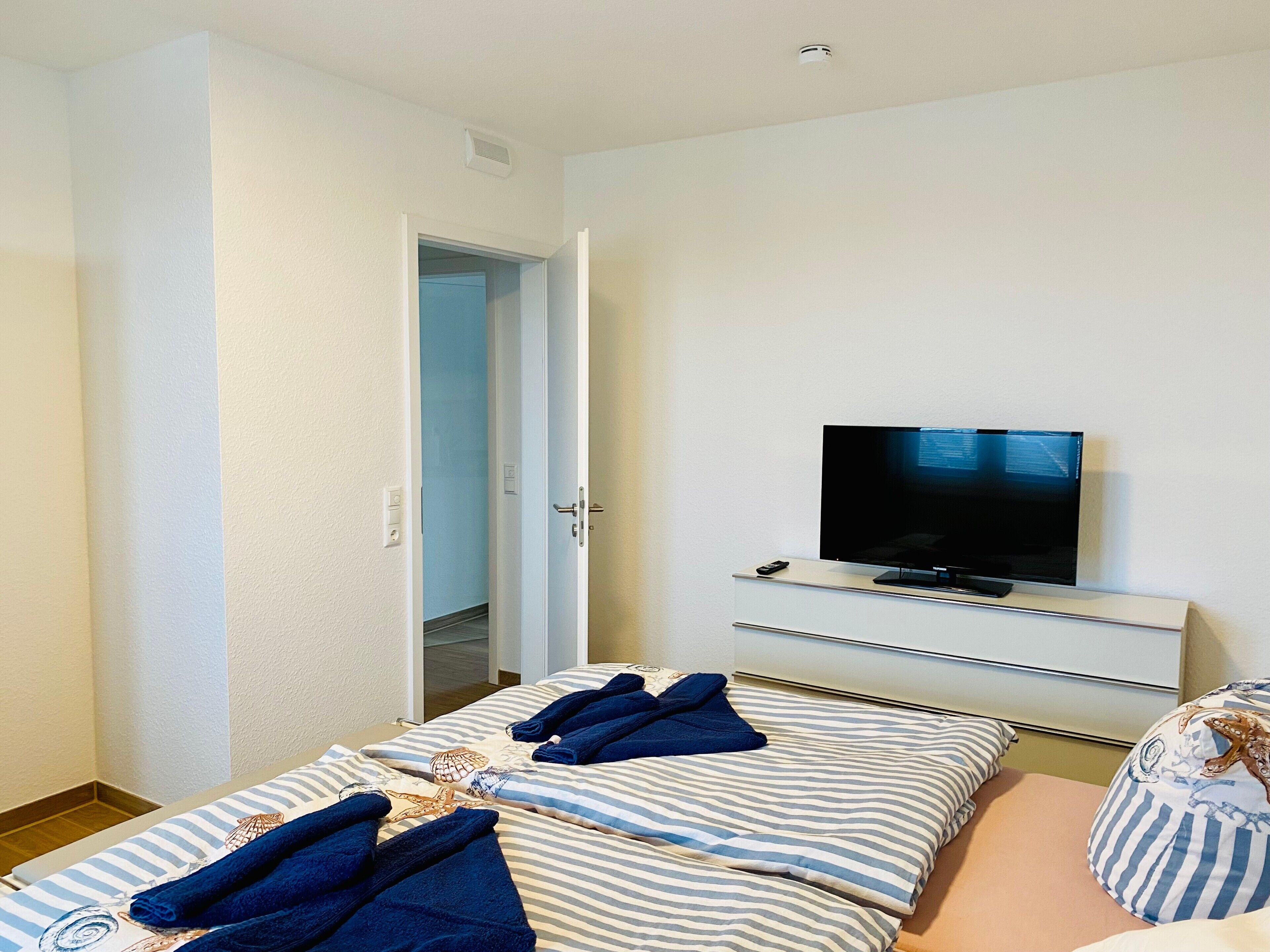 Ein Hotelzimmer mit Bett, Fernseher und einer Tür zu einem Badezimmer.