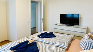 A hotel room with a bed, a TV, and a door leading to a bathroom. - Apartment 'Duhner Allee 10, Litfaß 17' with Balcony and Wi-Fi (Cuxhaven)