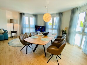 Un espace repas moderne avec une table en bois, des chaises marron et un luminaire suspendu.