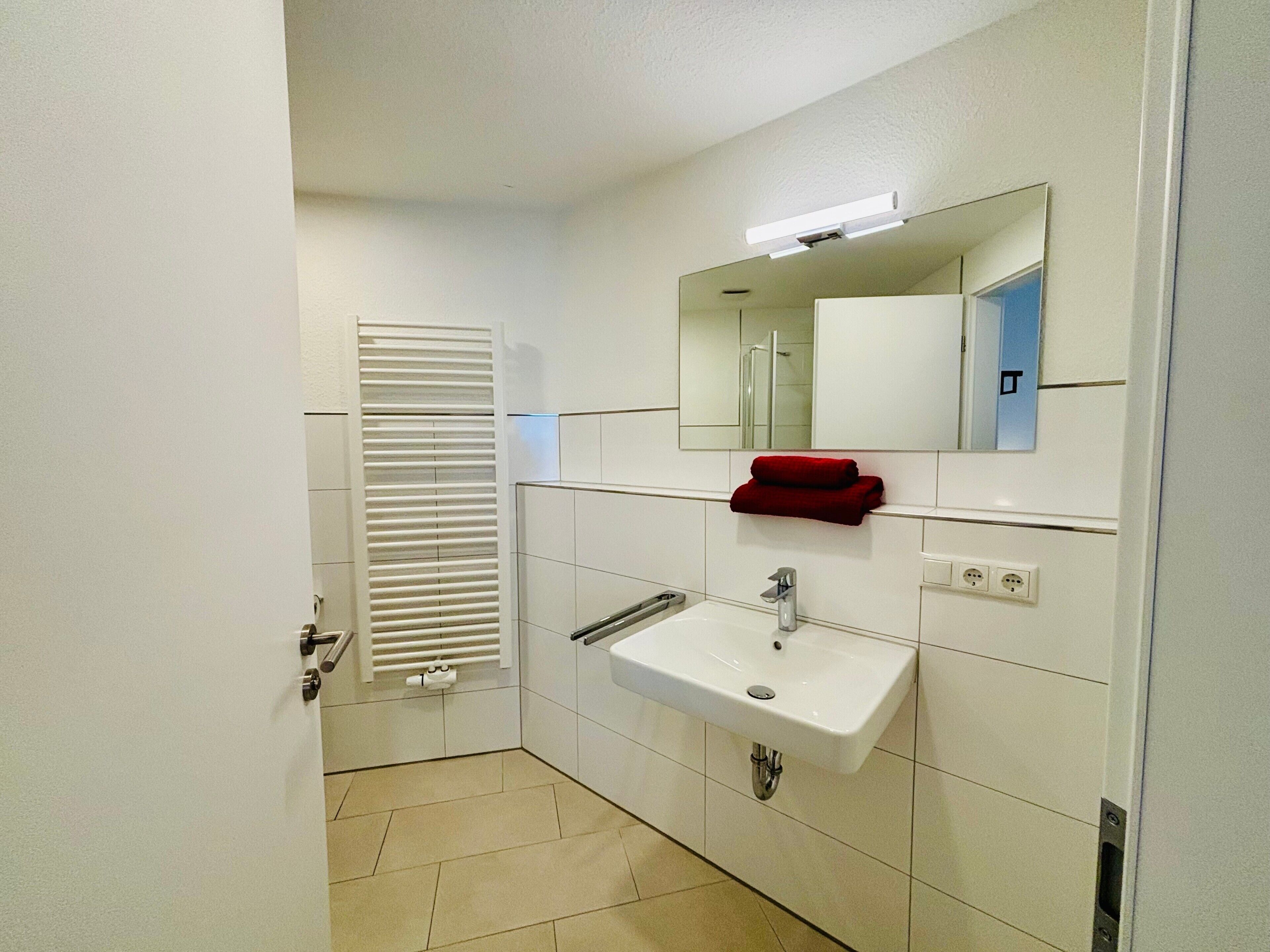 A bathroom with a white sink, mirror, and towel rack.