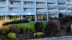 A multi-story hotel with balconies, a shop on the ground floor, and a well-maintained garden area. - Studio '307 Im Lord Nelson' with Sea View, Balcony and Wi-Fi (Cuxhaven)