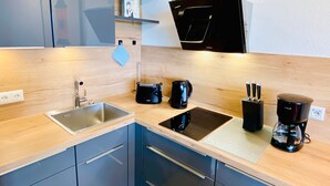 A modern kitchen with a sink, stove, and coffee maker. - Studio '307 Im Lord Nelson' with Sea View, Balcony and Wi-Fi (Cuxhaven)