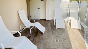 A sunlit room with white lounge chairs, a clock, and a door. - Studio '307 Im Lord Nelson' with Sea View, Balcony and Wi-Fi (Cuxhaven)