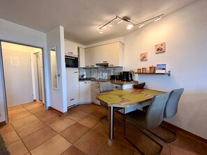 Cocina compacta con mesa, sillas y microondas.