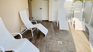 A sunlit room with white lounge chairs, a clock, and a door. - Apartment '109' with Balcony and Wi-Fi (Cuxhaven)