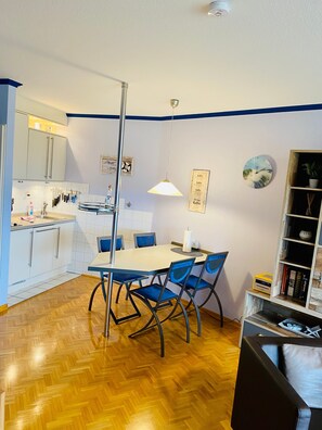 Una cucina moderna con mobili bianchi, un tavolo da pranzo con sedie blu e un pavimento in legno.