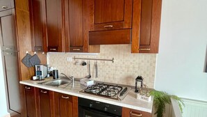 A kitchen with wooden cabinets, a gas stove, a built-in oven, and a tiled backsplash. - Attic Ancient Milan (San Giuliano Milanese)