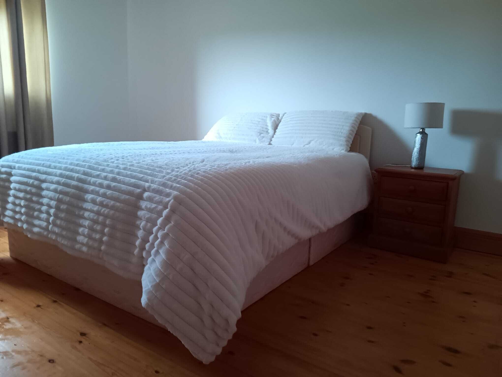 Un dormitorio con una cama, una mesita de noche y una lámpara.