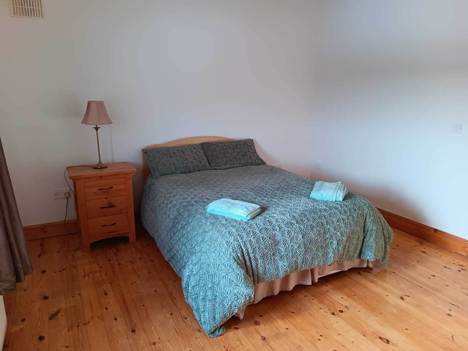 A bedroom with a bed, a nightstand, and a lamp.