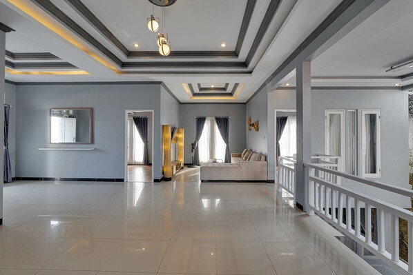 Un hall d’hôtel spacieux au design moderne, comprenant un grand espace salon, un miroir décoratif et un plafond bien éclairé grâce à des luminaires encastrés.
