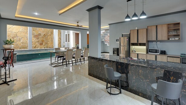 A modern kitchen with a marble countertop, bar stools, and a view of the dining area. - Villa Master Residance - Denpasar (Denpasar)