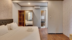 A bedroom with a large bed, a wooden wardrobe, a bathroom with a shower, and a kitchen area. - Villa Master Residance - Denpasar (Denpasar)