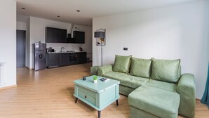 A modern living room with a green sofa, a light blue coffee table, and a kitchen in the background. - Apartment in historic Tbilisi (Tbilisi)