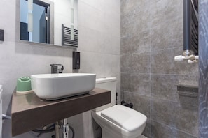 A modern bathroom with a large white sink, a toilet, and a towel rack.