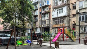 A playground with a pink slide and swings, surrounded by apartment buildings. - Apartment in historic Tbilisi (Tbilisi)