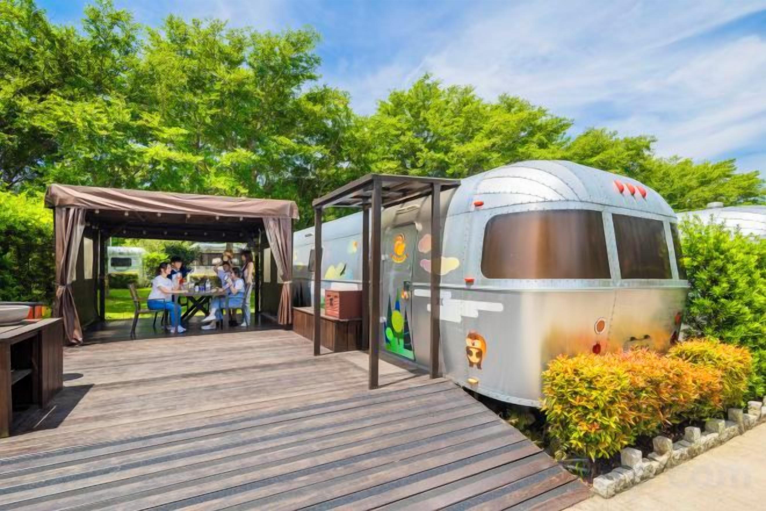 A recreational vehicle with a covered patio area and a group of people dining.