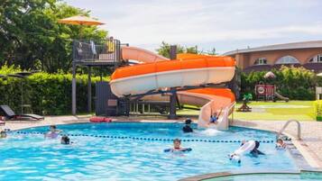 A swimming pool with a water slide and lounge chairs.