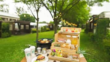 An outdoor picnic setup with a wooden table, food items, and Starbucks cups.