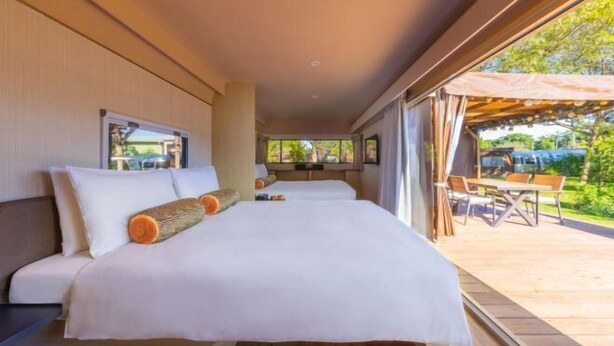 A modern hotel room with a large bed, a view of the outdoor patio, and a window overlooking the greenery. - Bon Chill Glamping By Cosmos Otium (Taoyuan)