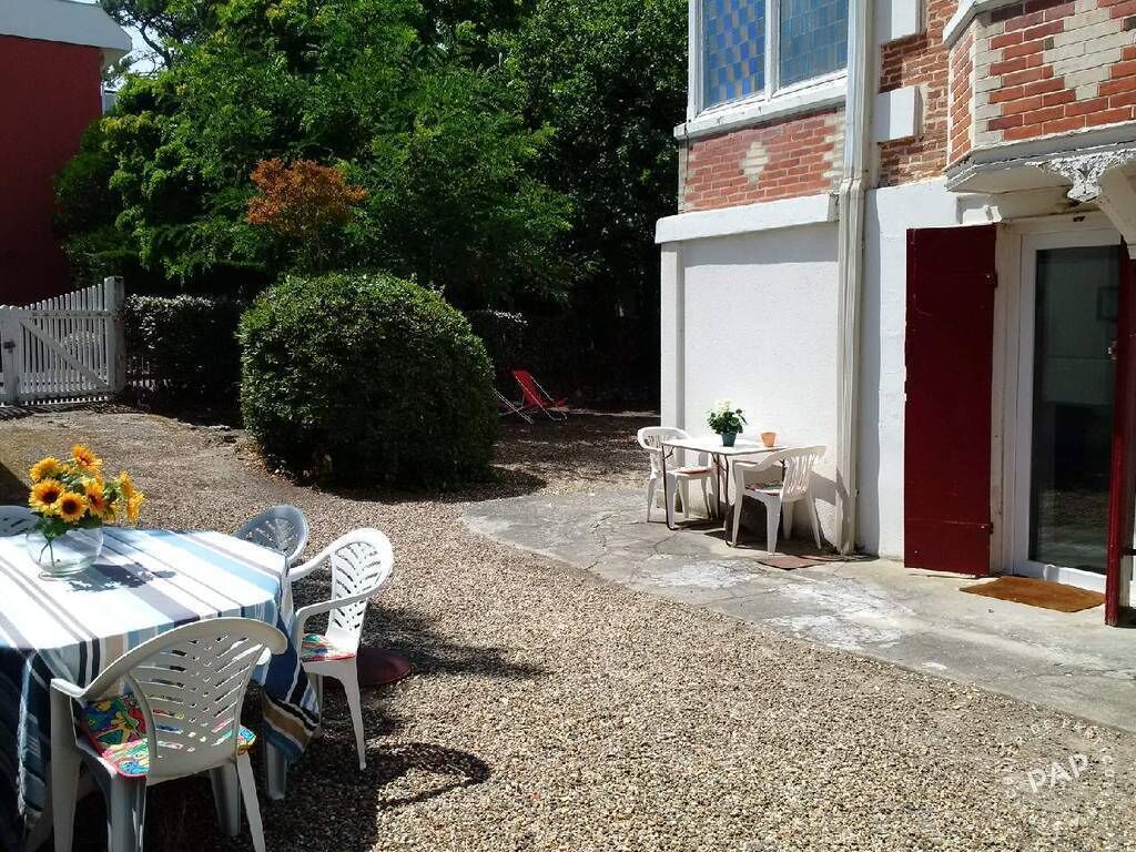 A patio area with a table and chairs, a small round table with a plant, and a red door.